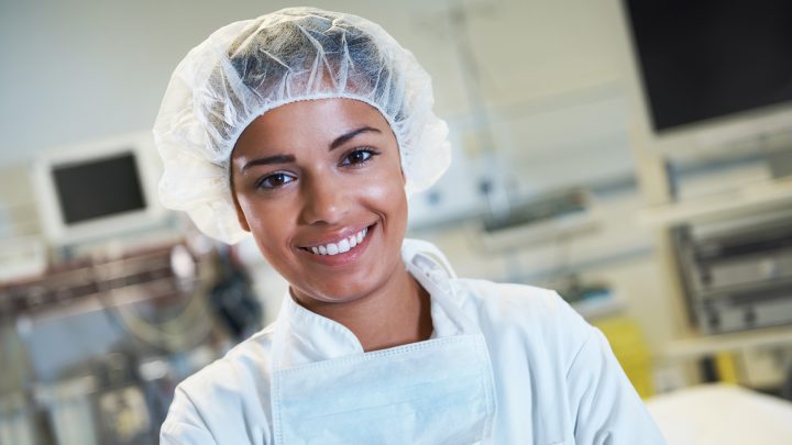 A food tech worker smiling wearing a hair net