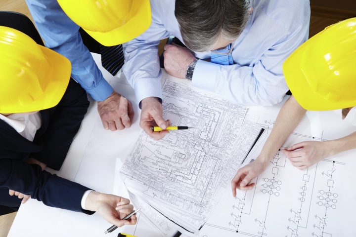 A group of men wearing hard hats working on a blueprint.