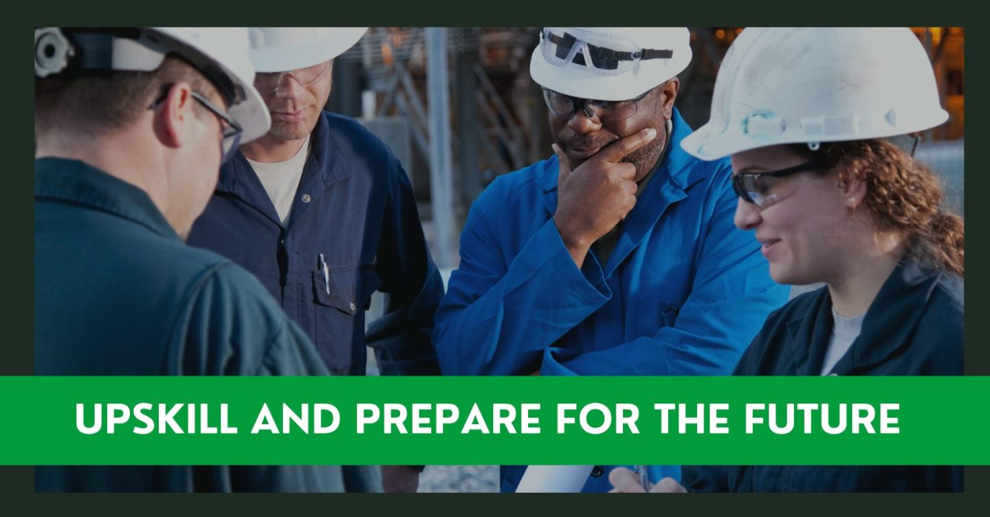 four people in white hard hats and safety glasses looking at a blueprint