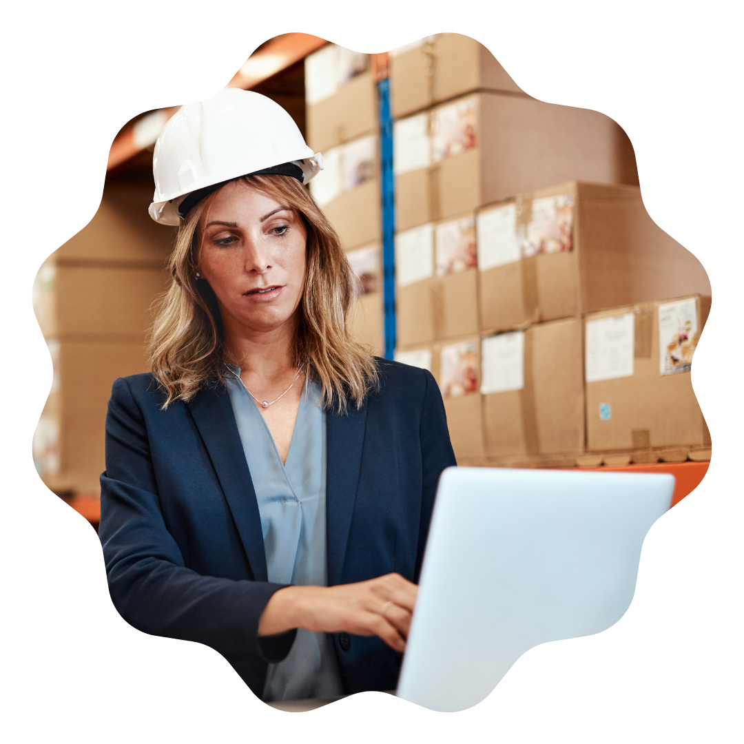 A professional woman in a hard hat and suit is focused on her laptop while working diligently.