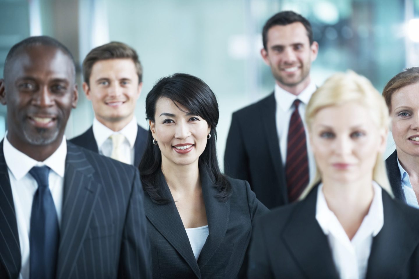 group of men and woman wearing suits in a corporate sales office space