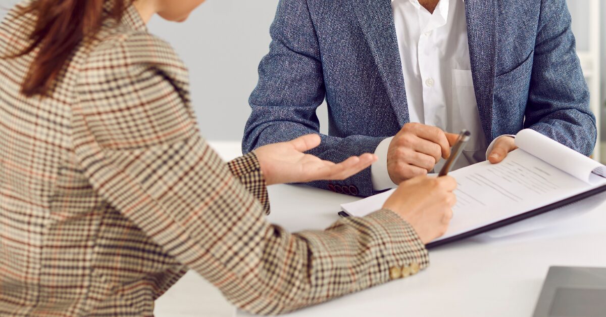 a man and woman sitting with a notepad writing a resume