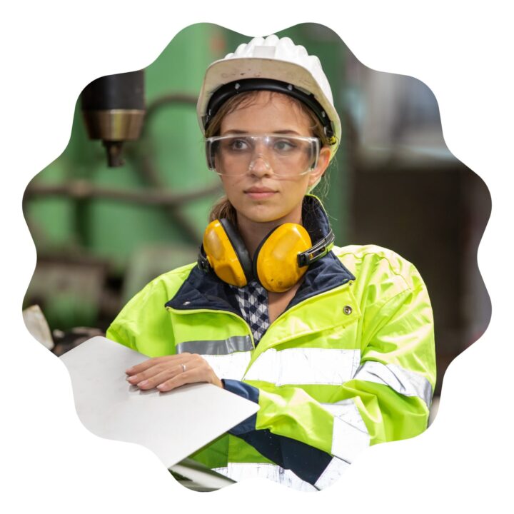 a woman in a hard hat and safety glasses in safety gear holding a laptop as a technical engineer