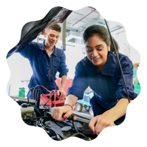 two diesel mechanics, a man and woman, working on a car in a garage