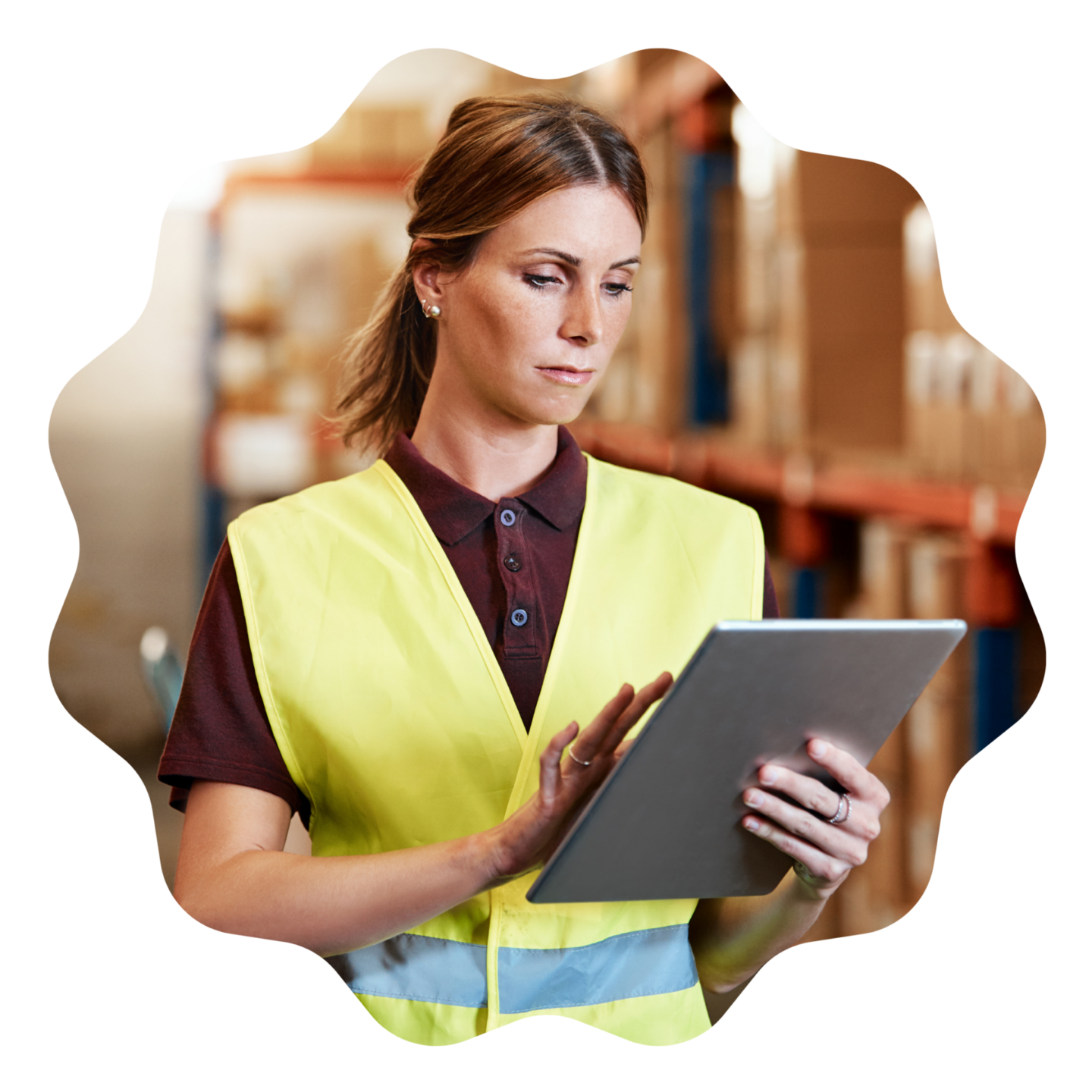 a supply chain manager wearing a yellow hi vis holding a tablet in a warehouse