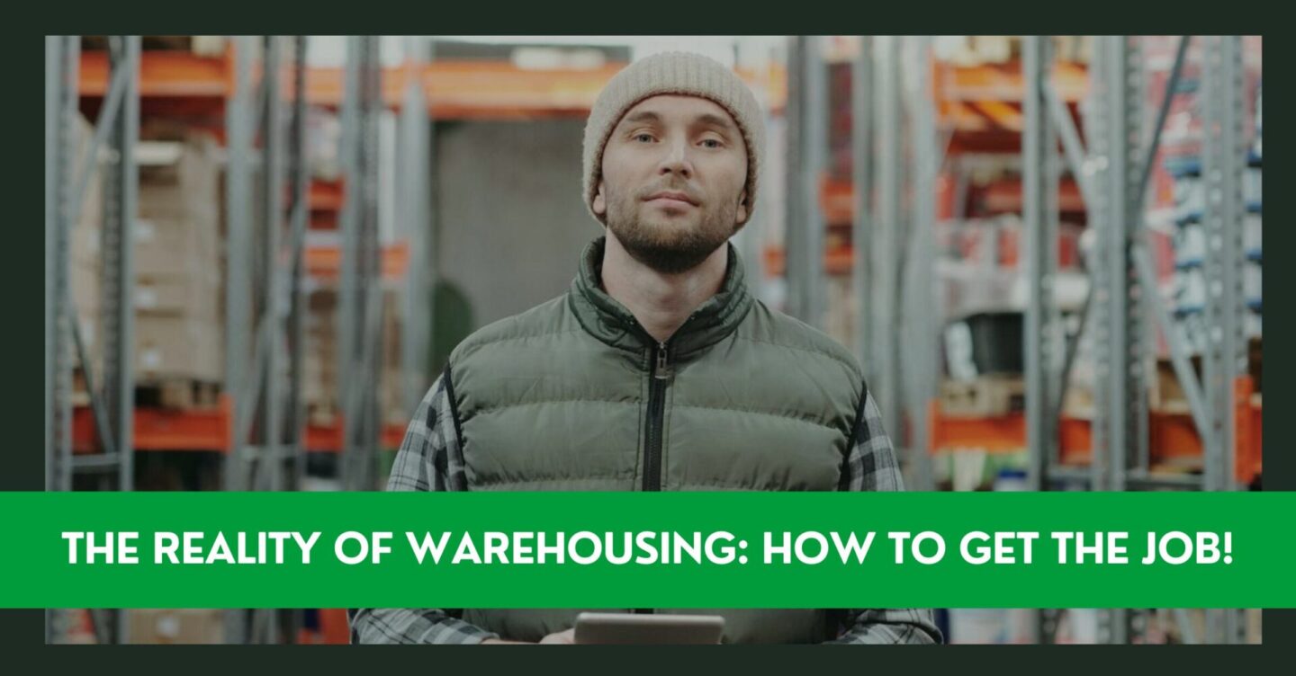 A man wearing a grey beanie and puffer vest is standing in a warehouse holding a tablet